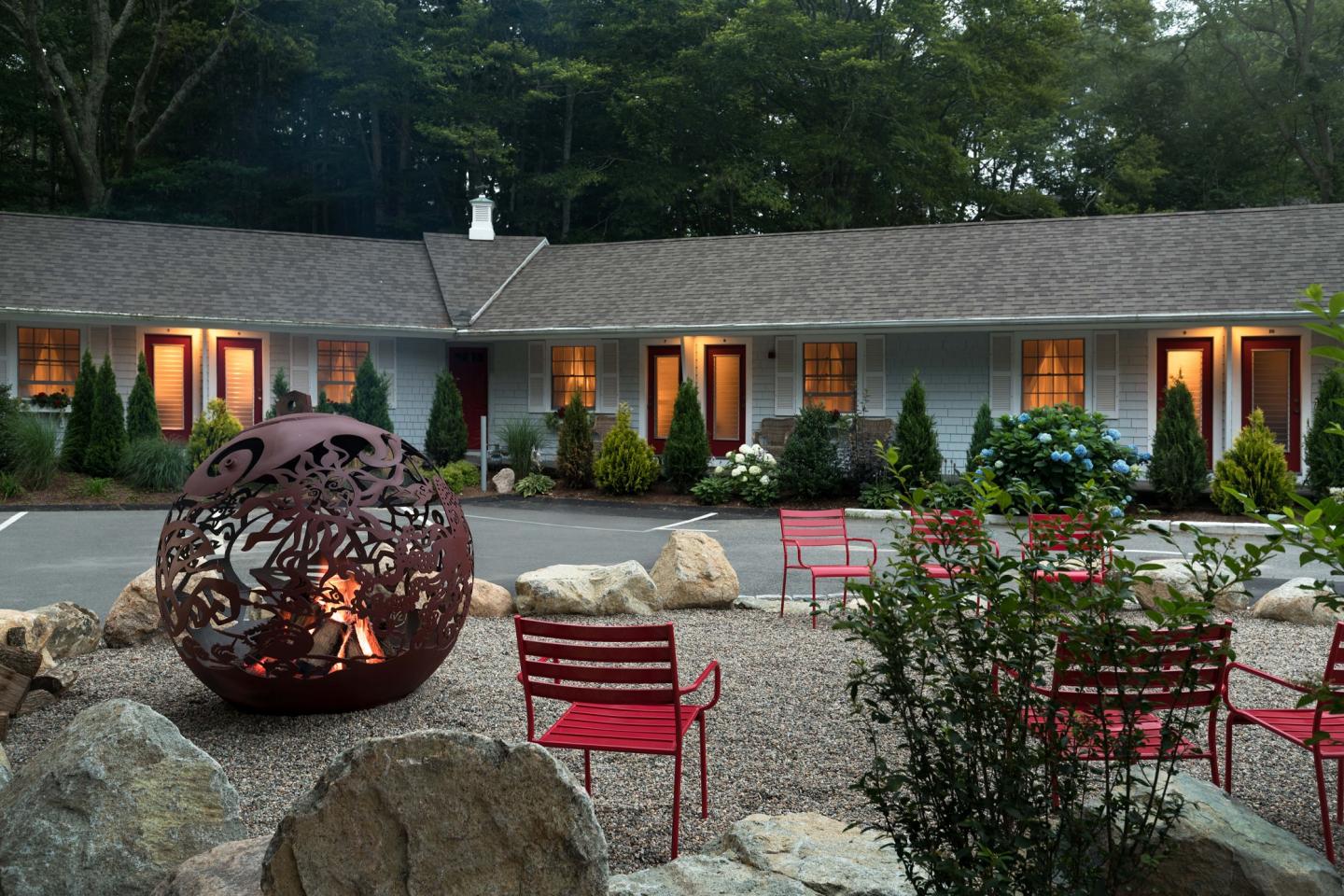 Cozy motel courtyard with red chairs and a fire pit.