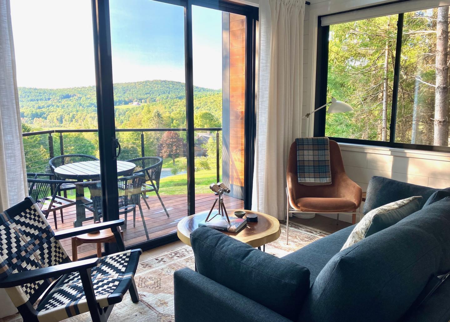 Cozy living room with mountain view through large windows and balcony.