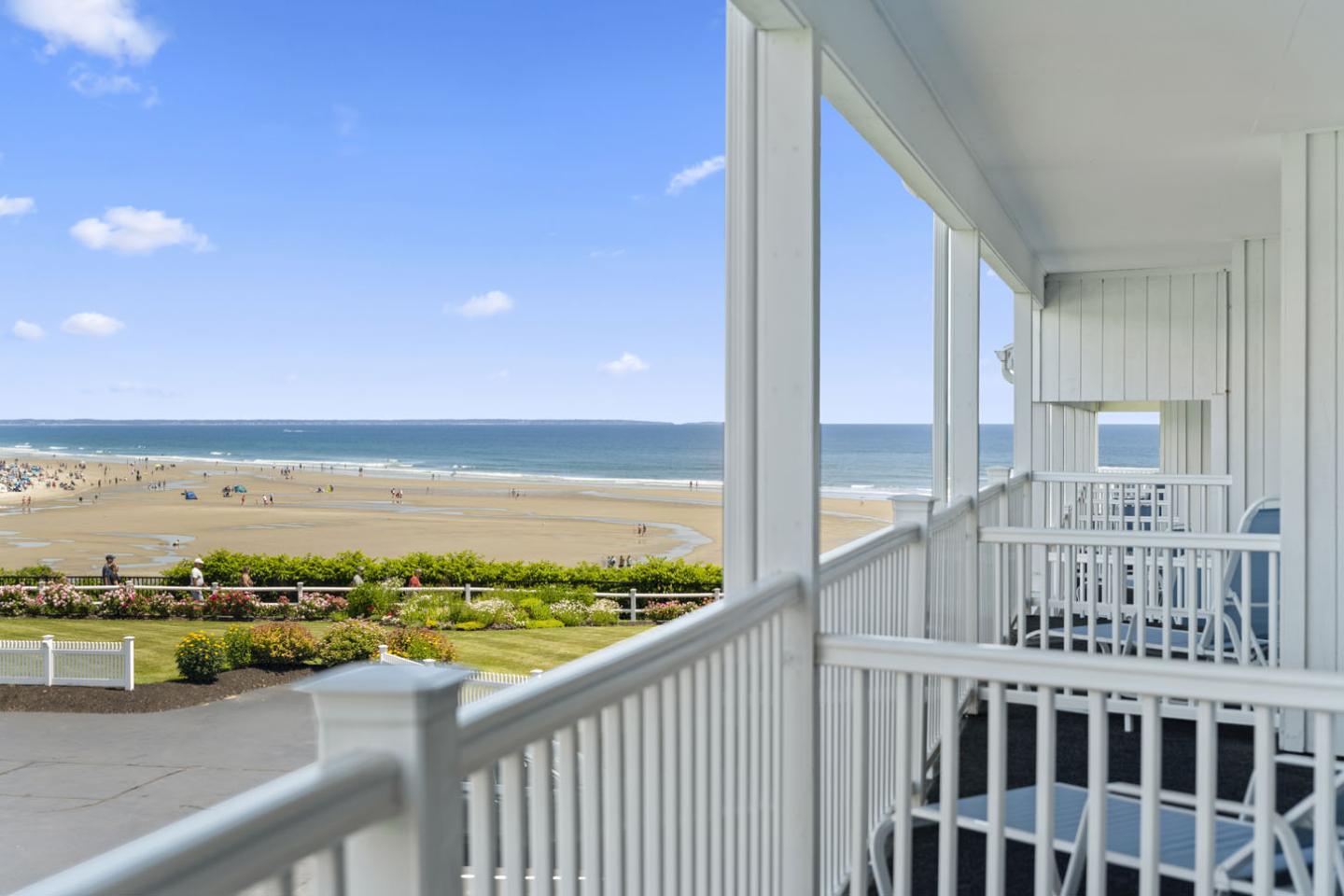 Ocean view from a balcony with blue sky and sandy beach.