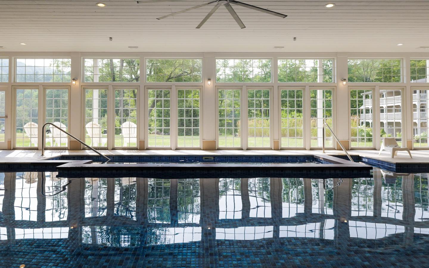 Indoor pool with large windows and a view of trees.