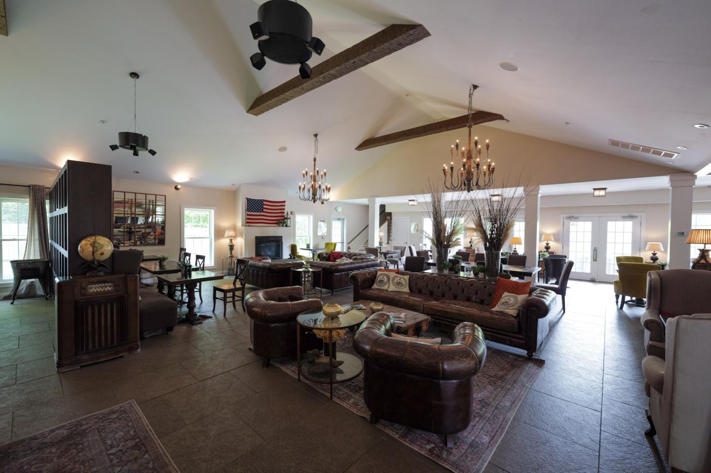 Spacious lounge with leather sofas, chandeliers, and large windows.