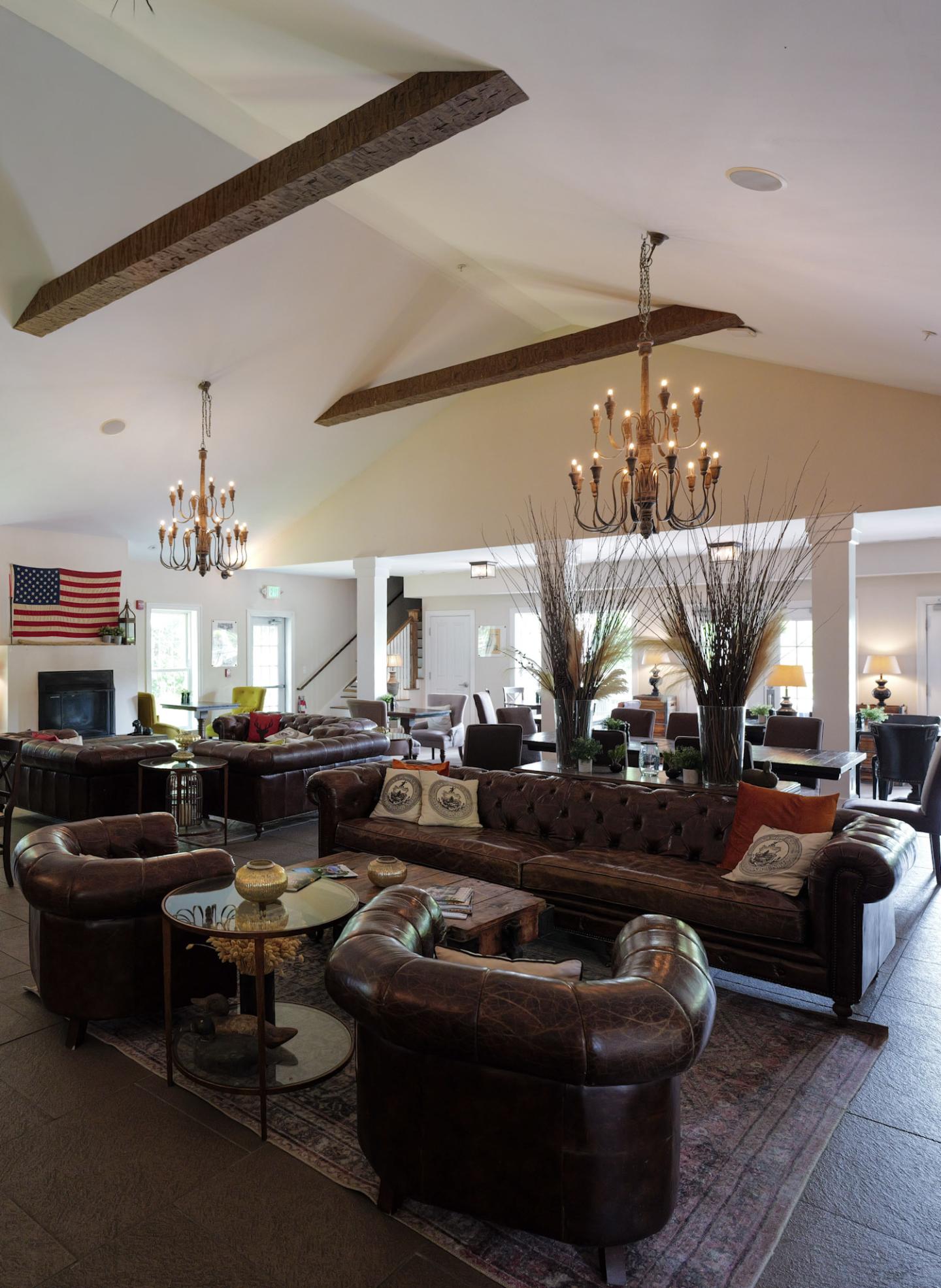 Luxurious lounge with leather sofas, chandeliers, and a rustic American flag decor.