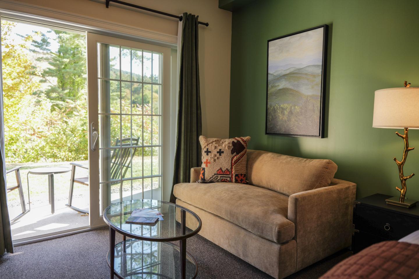 Cozy room with a sofa, glass table, and patio doors leading to a garden view.