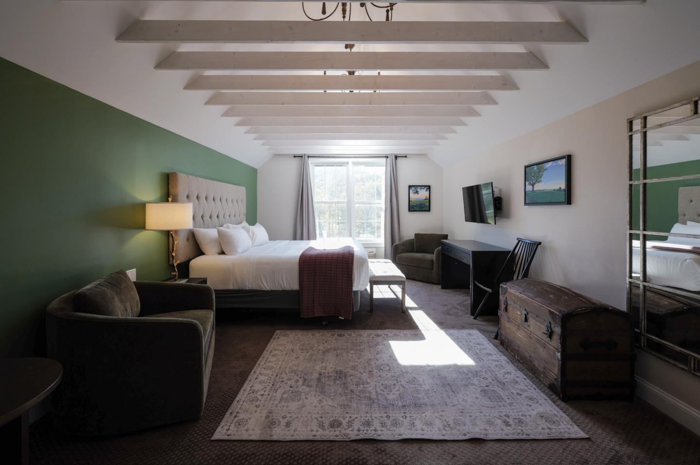 Stylish hotel room with a bed, armchairs, and a window.