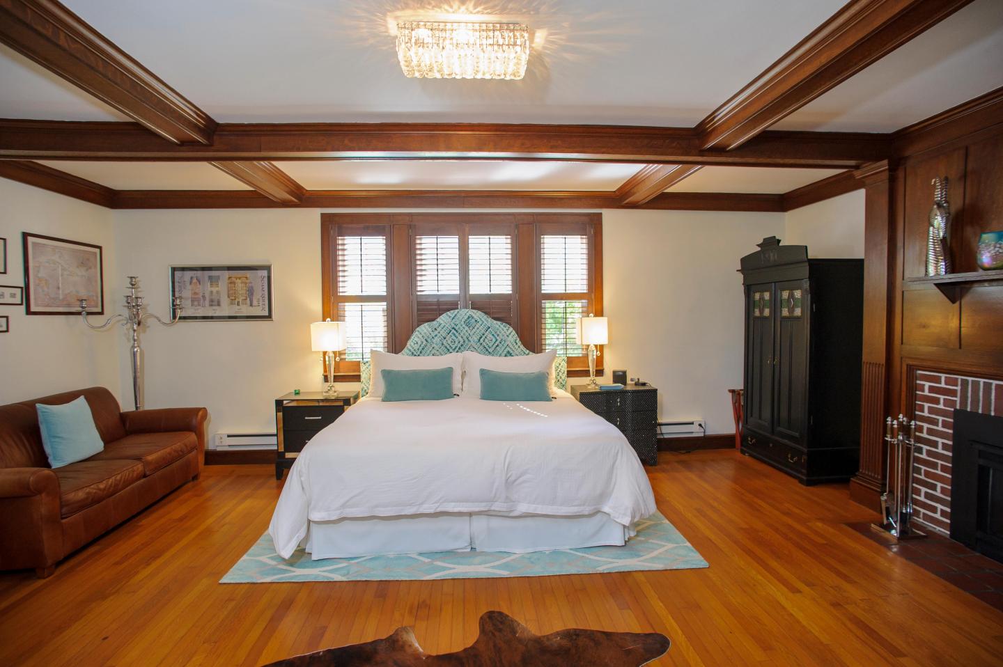 Luxury Grand bedroom with a large bed, wooden floors, and a chandelier.