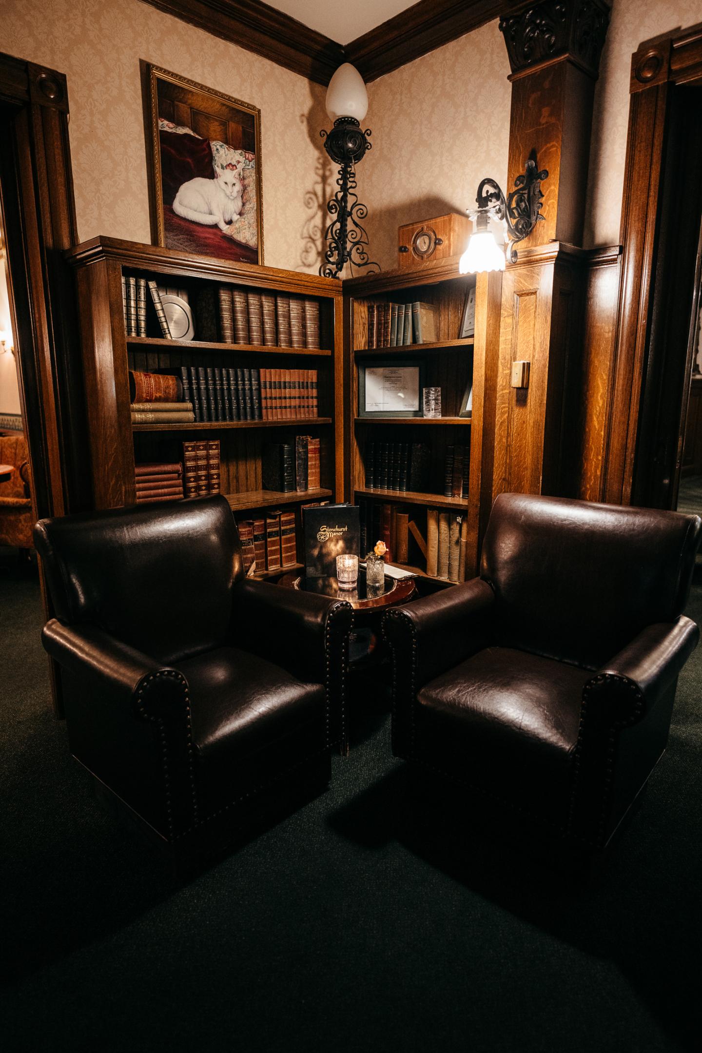 Cozy library nook with two leather chairs and bookshelves.