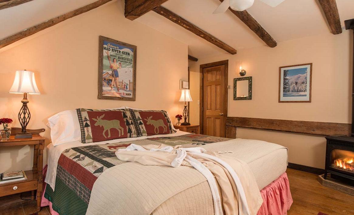 Cozy bedroom with rustic decor, double bed, wooden beams, and a lit fireplace.