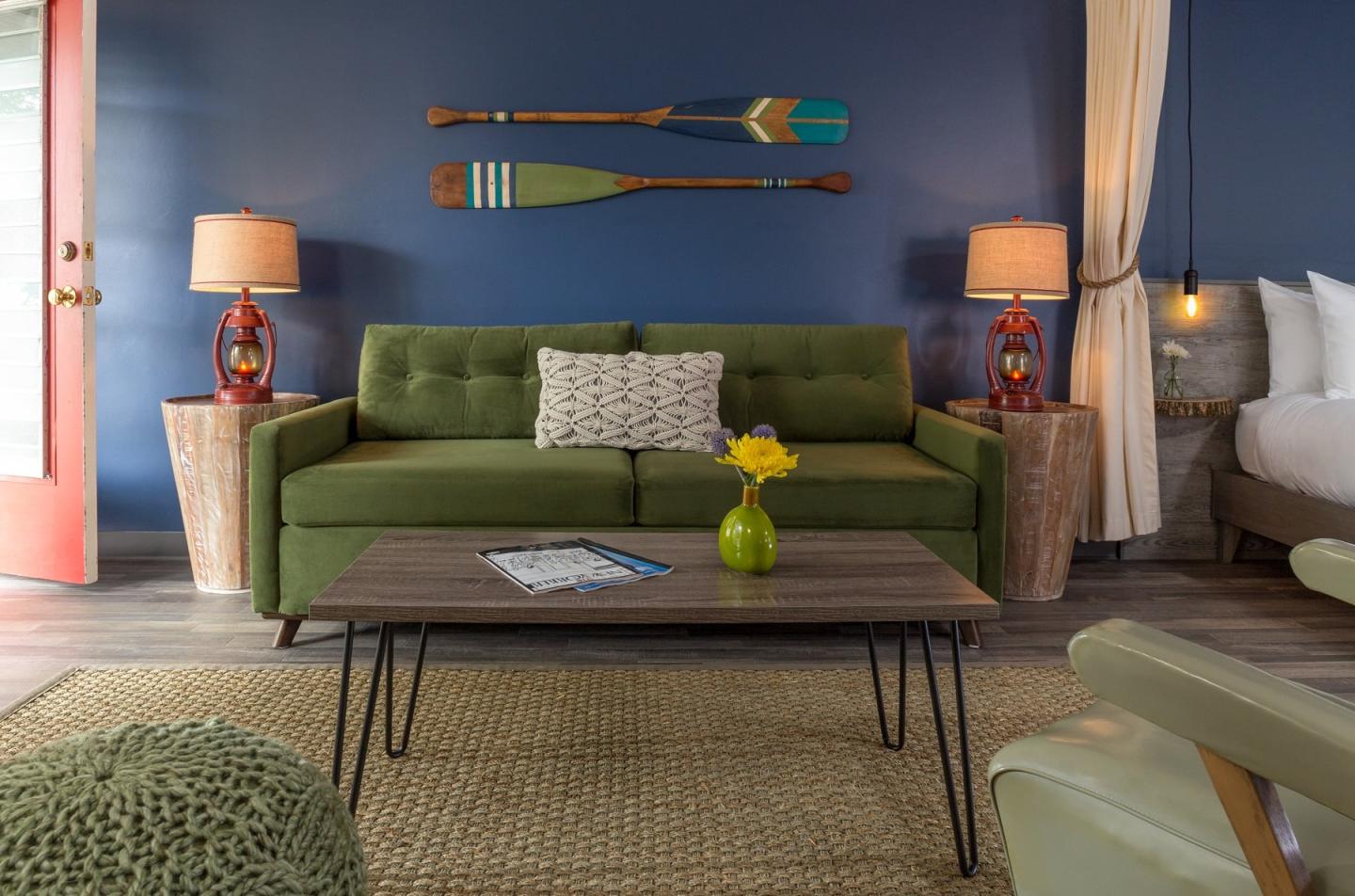 Cozy living room with green sofa, wooden table, and oars on blue wall.