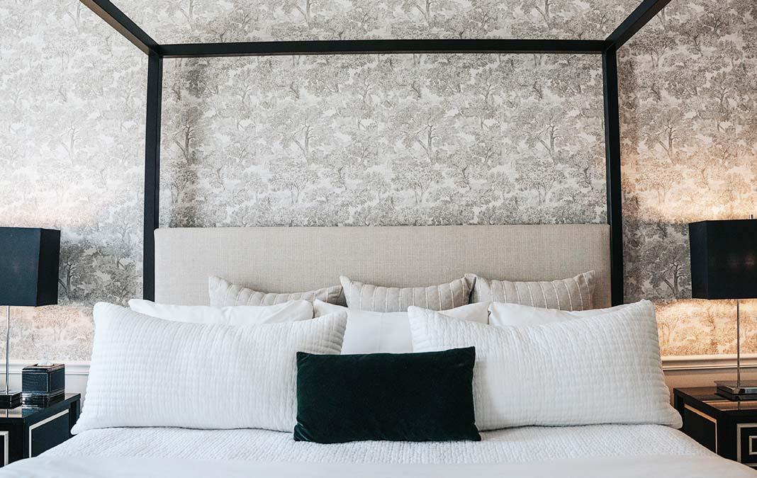 Canopy bed with white pillows and a dark cushion.