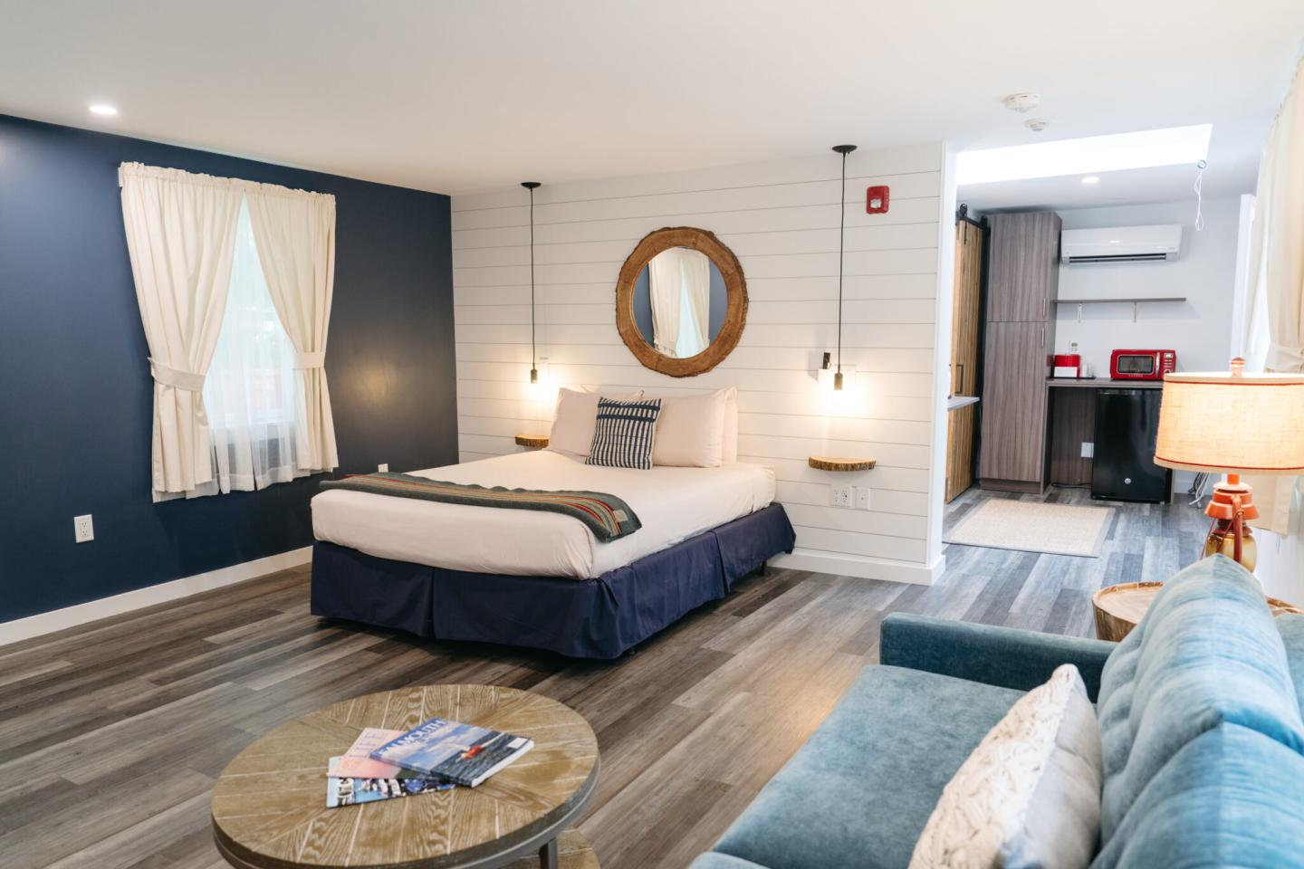 Cozy hotel room with bed, sofa, and wooden flooring. Bright and inviting decor.