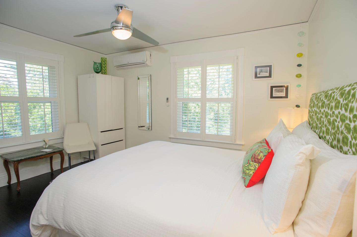 Cozy bedroom with white decor, a bed, and a green accent pillow.