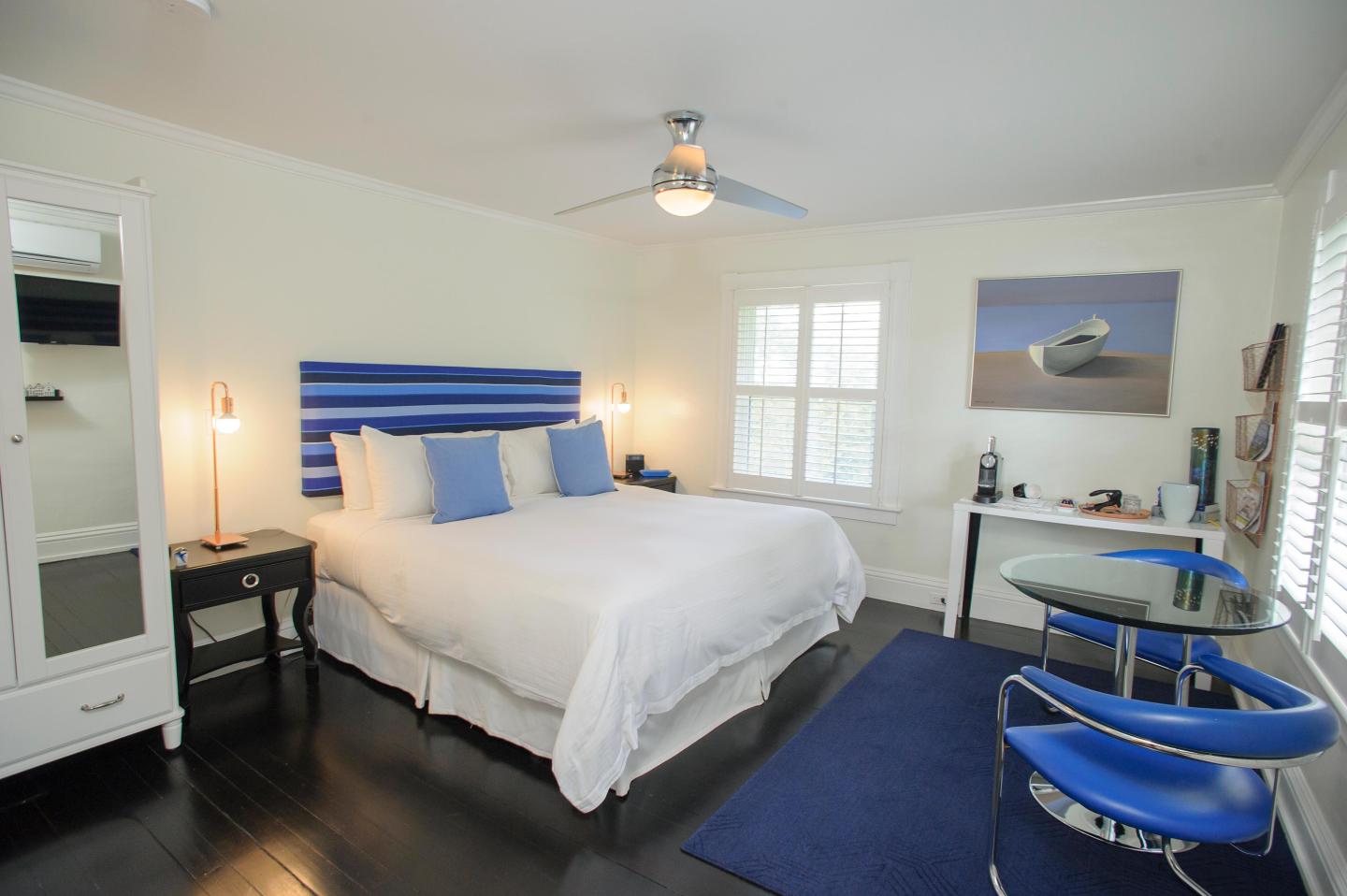 Deluxe bedroom with blue and white decor, dark floor, and ceiling fan.