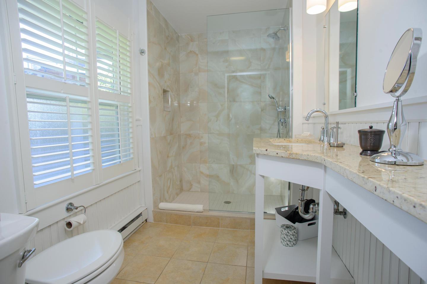 Bright bathroom with marble shower and granite countertop.