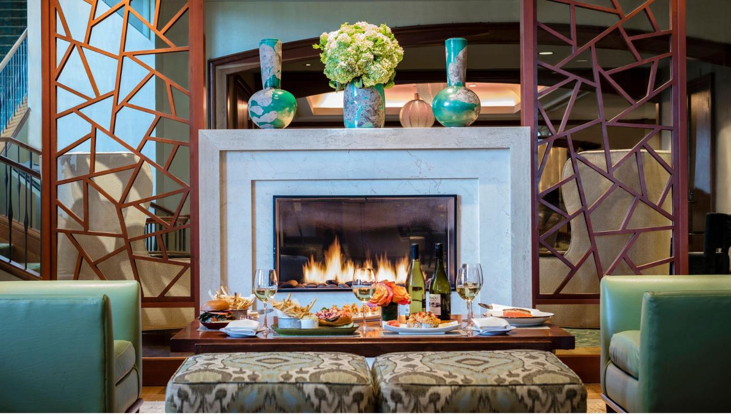 Elegant hotel lounge with a fireplace, food, and floral decor.