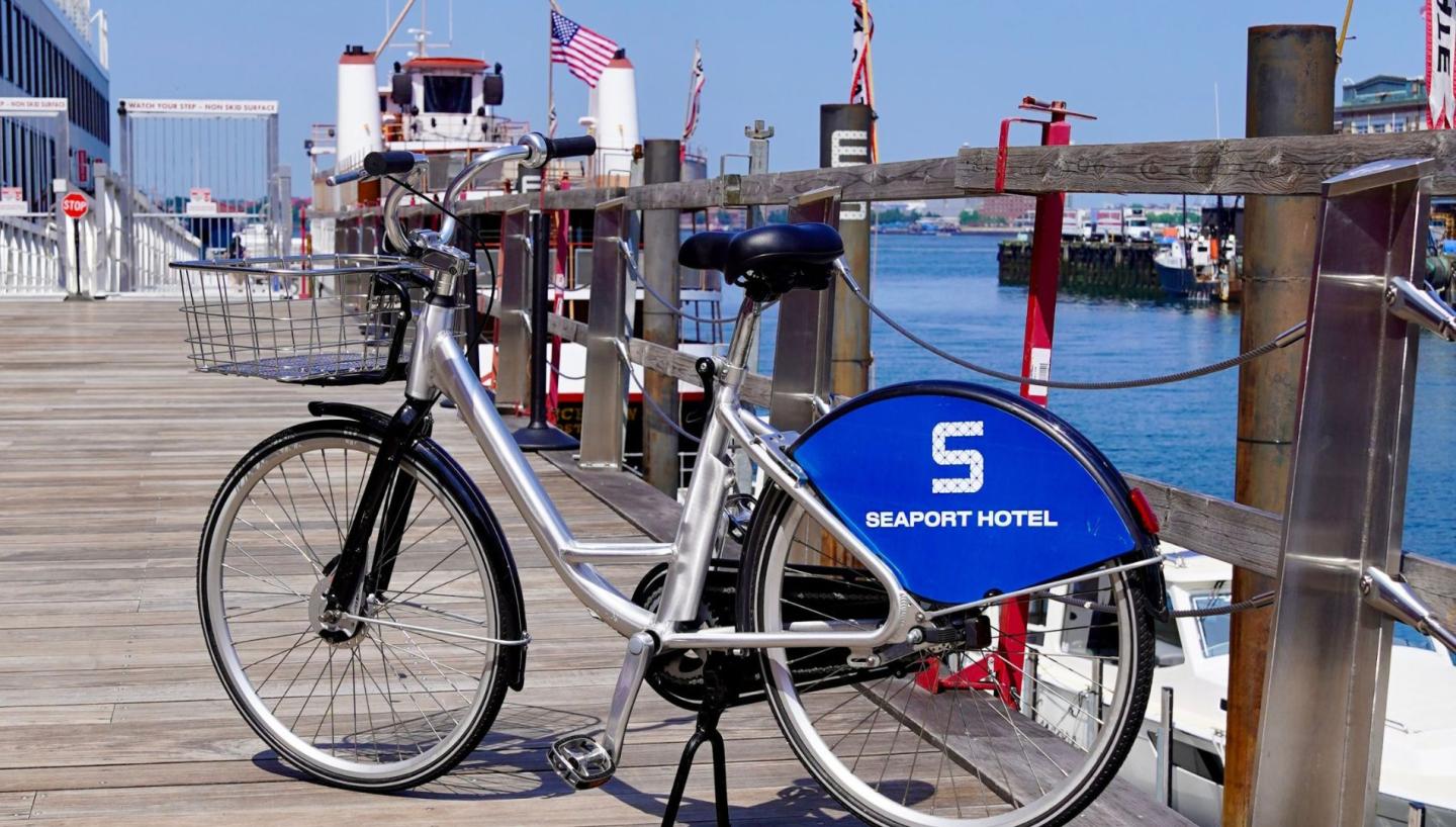 A bicycle parked on a wooden pier near a harbor.