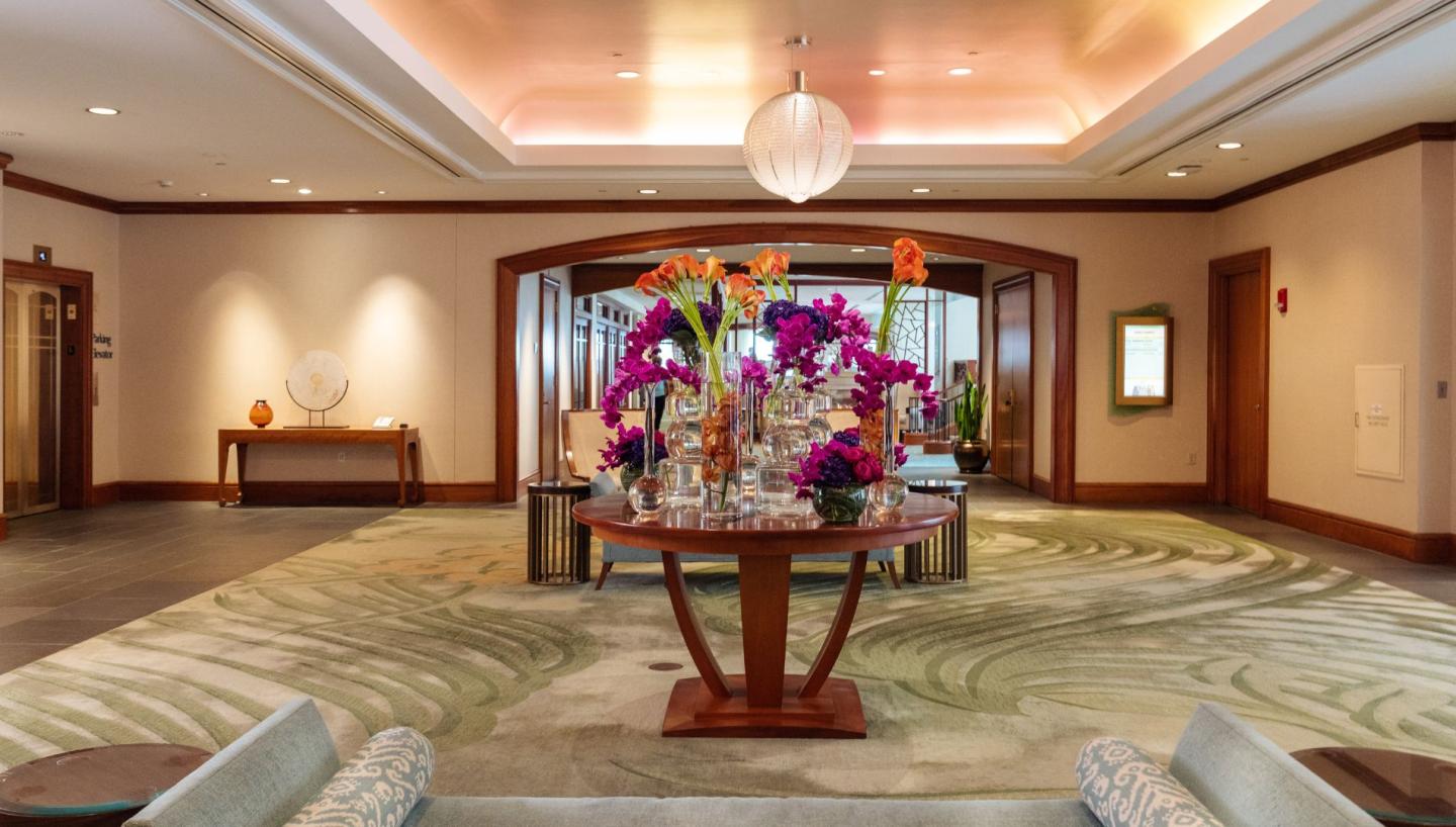 Spacious hotel lobby with a round table of vibrant flowers.