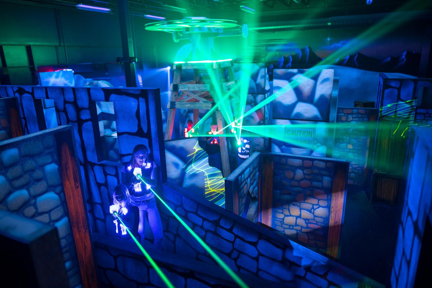 Laser tag arena with neon lights and players in vests.