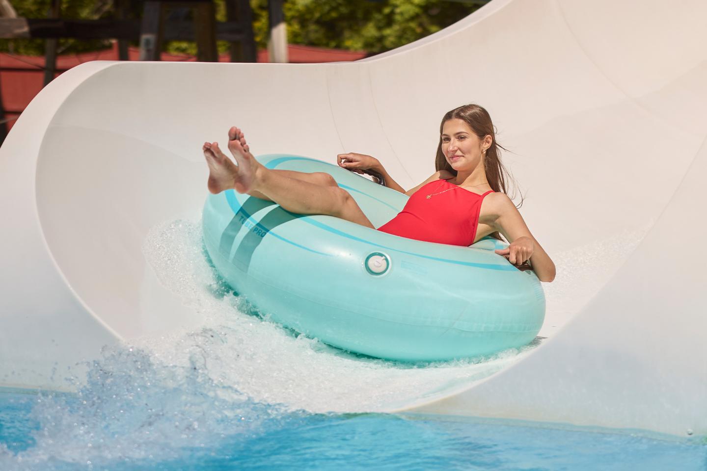 Woman in red swimsuit sliding down water slide in a blue inflatable tube.