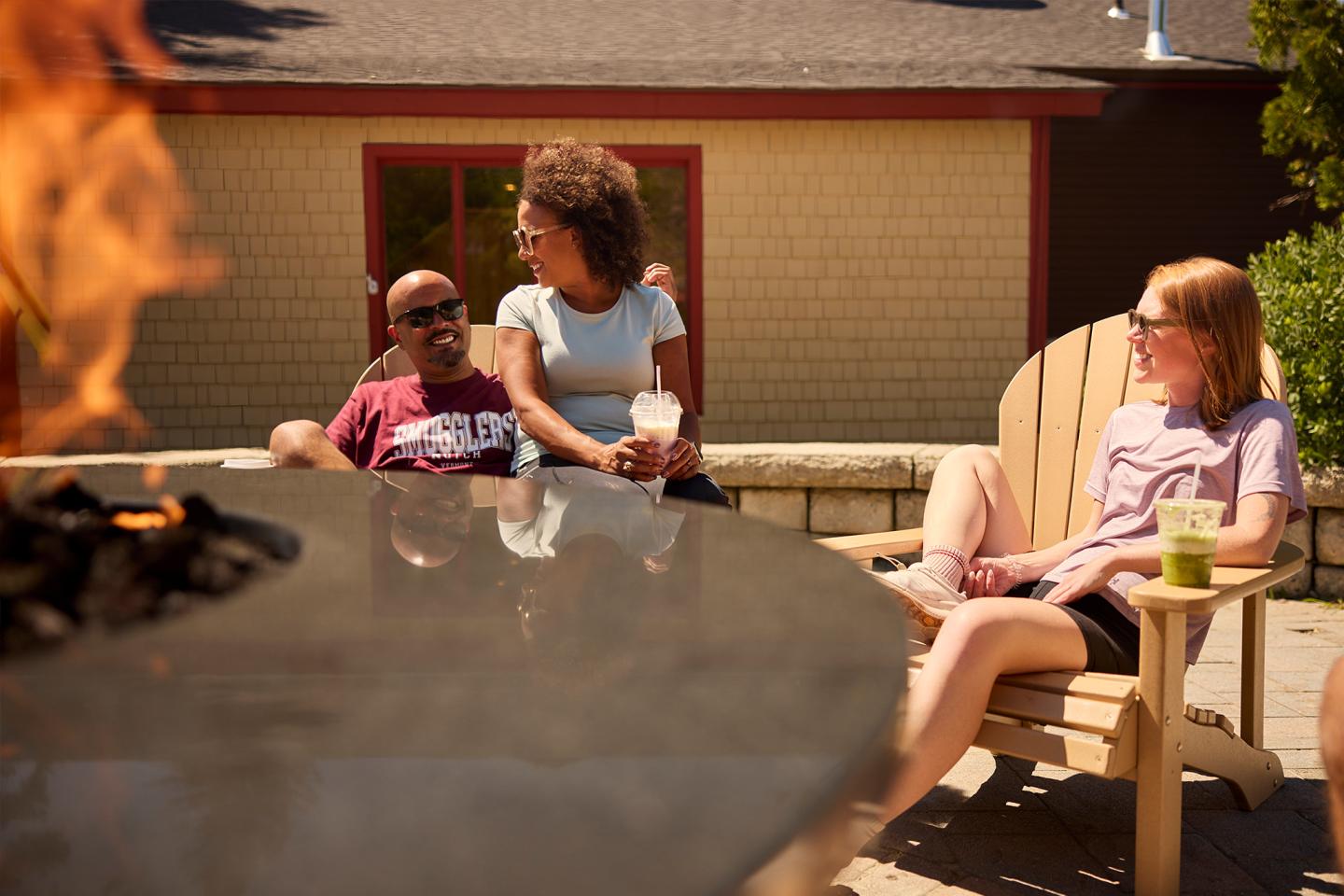 Group relaxing by outdoor fire pit on a sunny day.