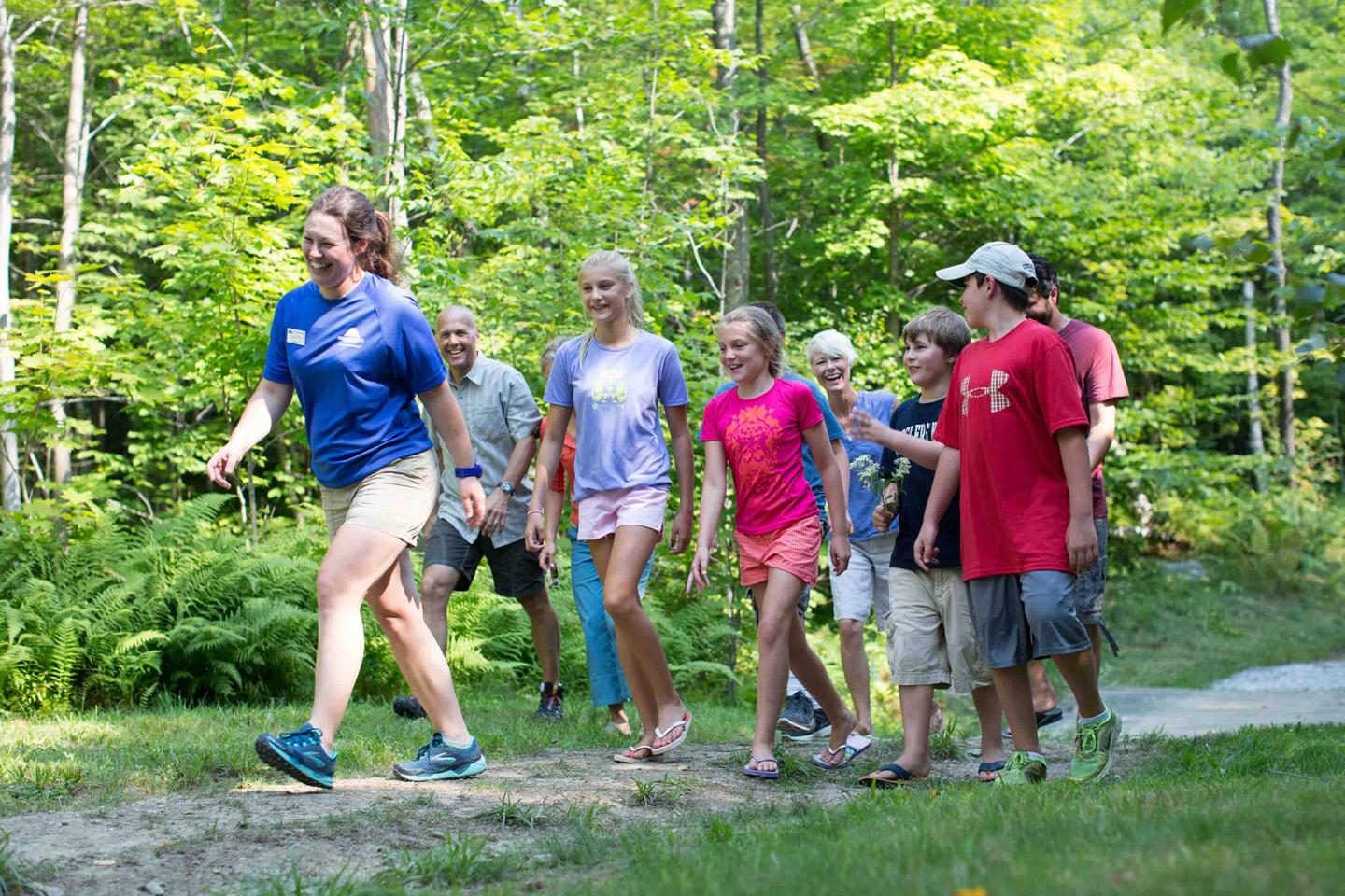 A group of people walking on a forest trail on a sunny day.