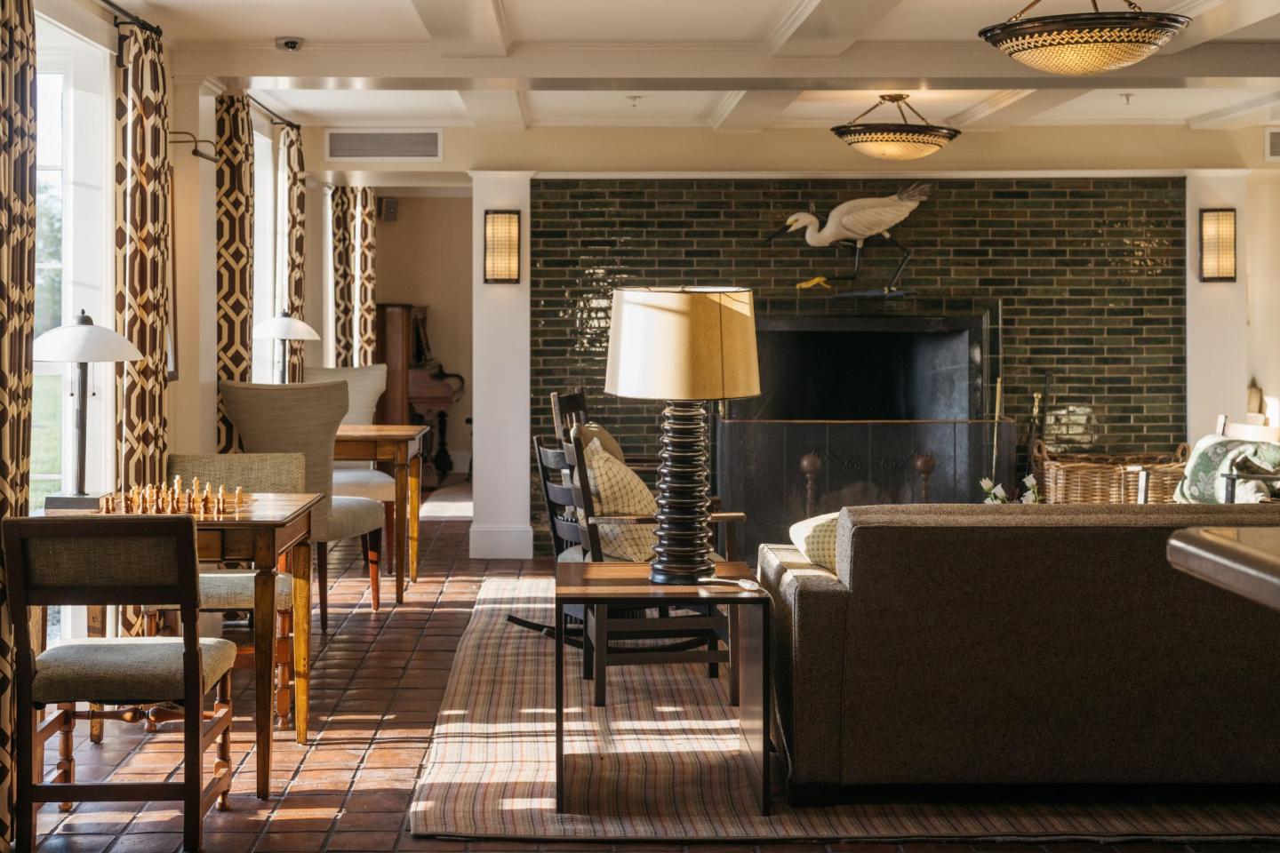 Elegant lounge with sofas, chess table, and large fireplace. Warm lighting and decor.