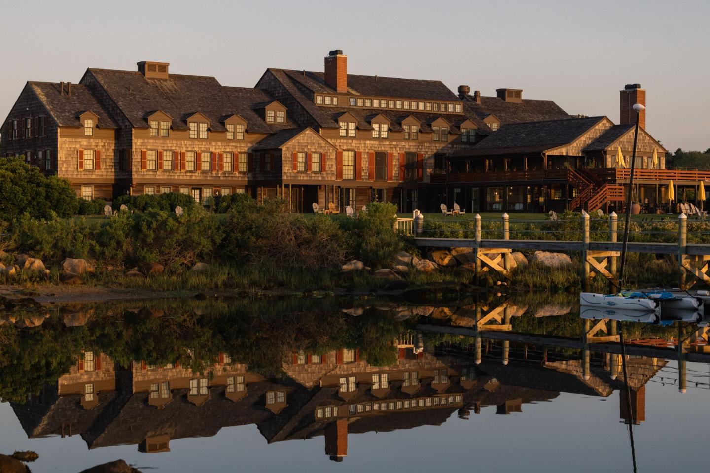 Large brick building reflecting on calm water at sunrise.