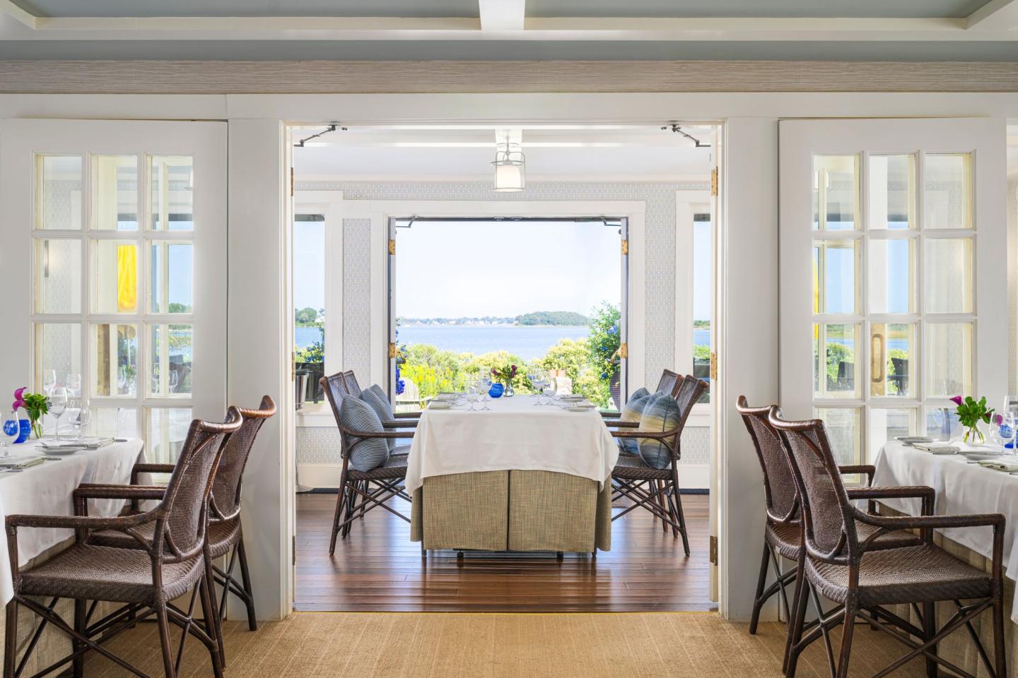Elegant dining room with ocean view and wicker chairs.