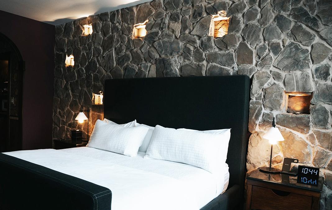 Cozy bedroom with stone accent wall and modern lighting.