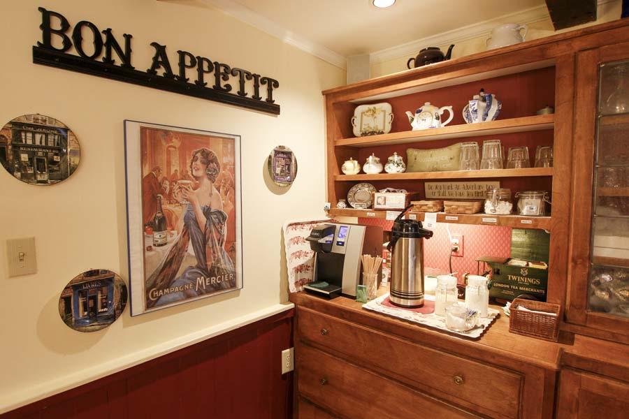 Cozy kitchen wall with a coffee station, art, and teapot collection.