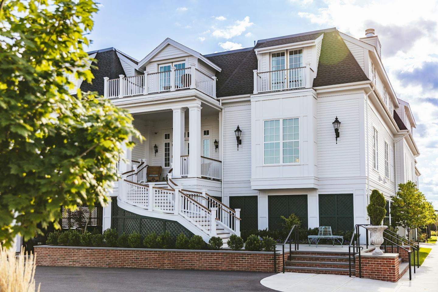Grand white house with columns and a large front staircase, sunny day.
