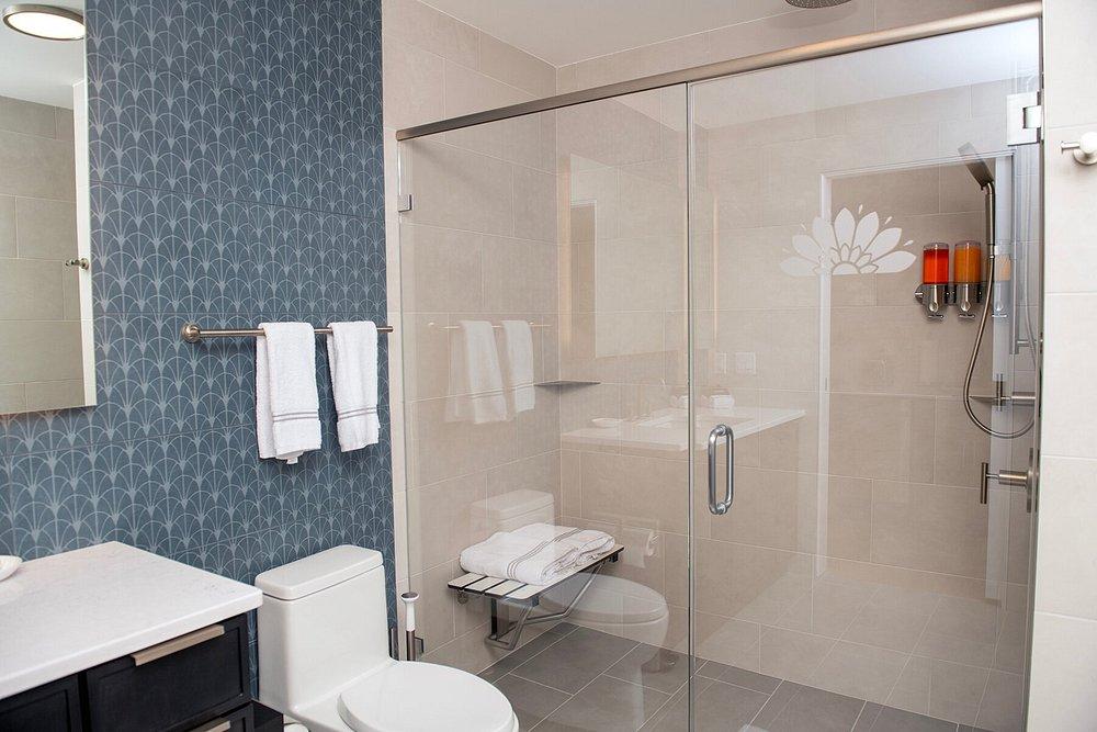 Modern bathroom with a glass shower, blue accent wall, and white towels.