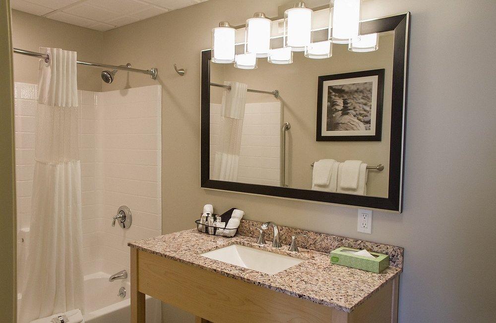 Bathroom with granite countertop, large mirror, and shower curtain.