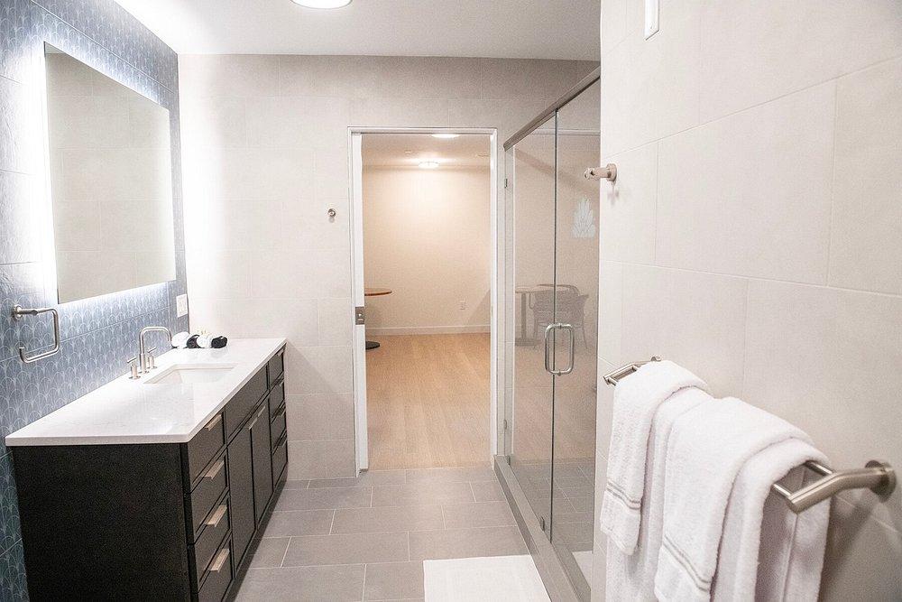 Modern bathroom with glass shower, vanity, and towels on rack.