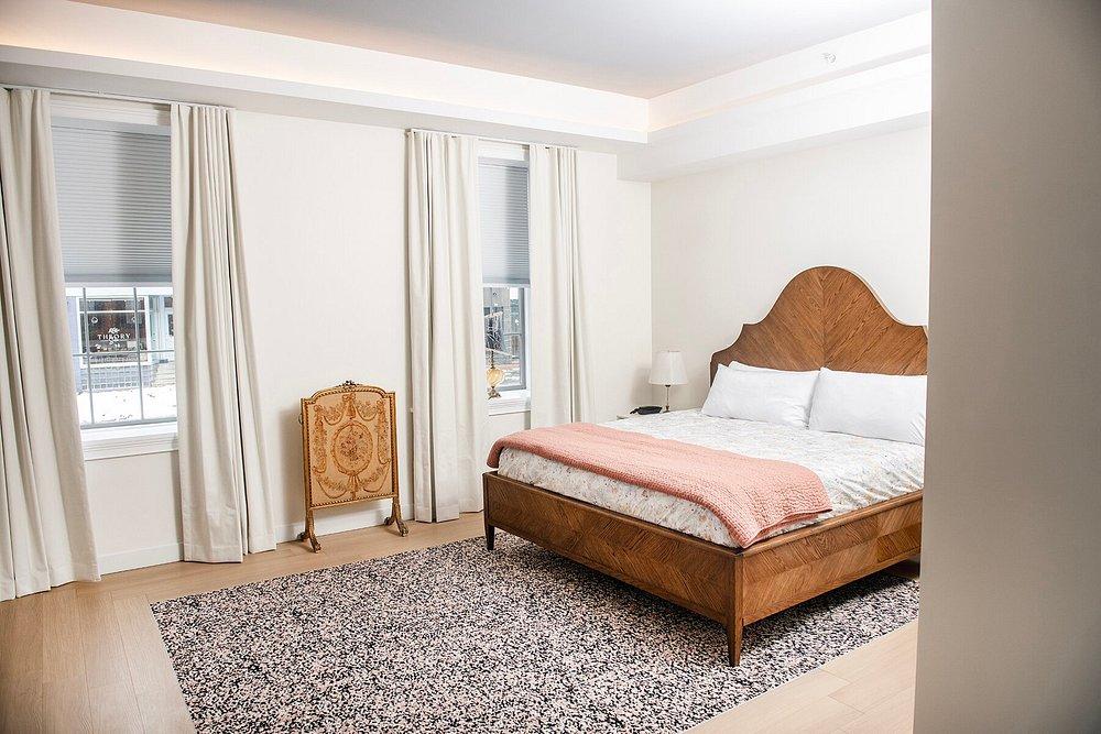 Cozy bedroom with a wooden bed, peach cover, and pale curtains.