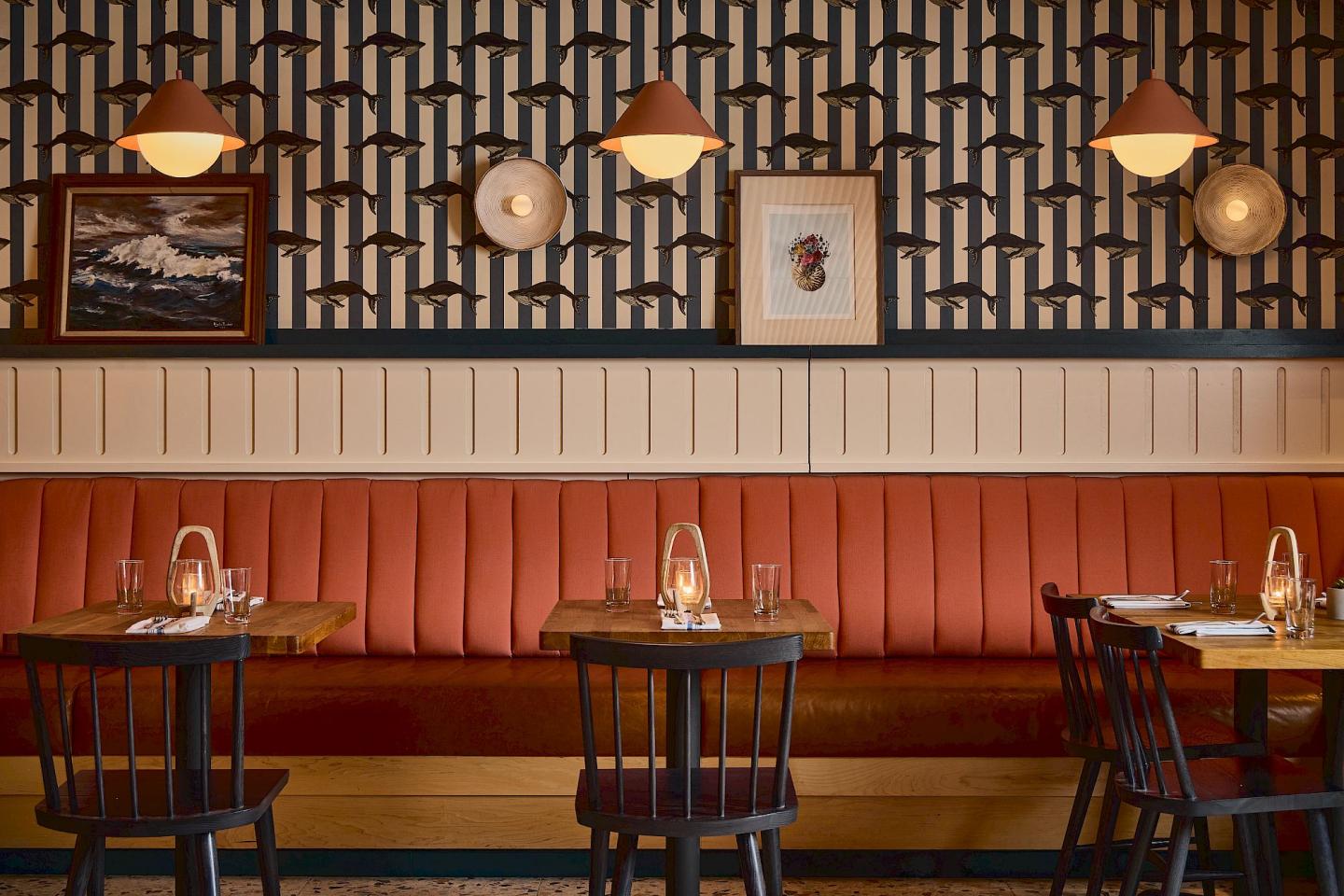 Cozy restaurant with red booth, wooden tables, and warm lighting.