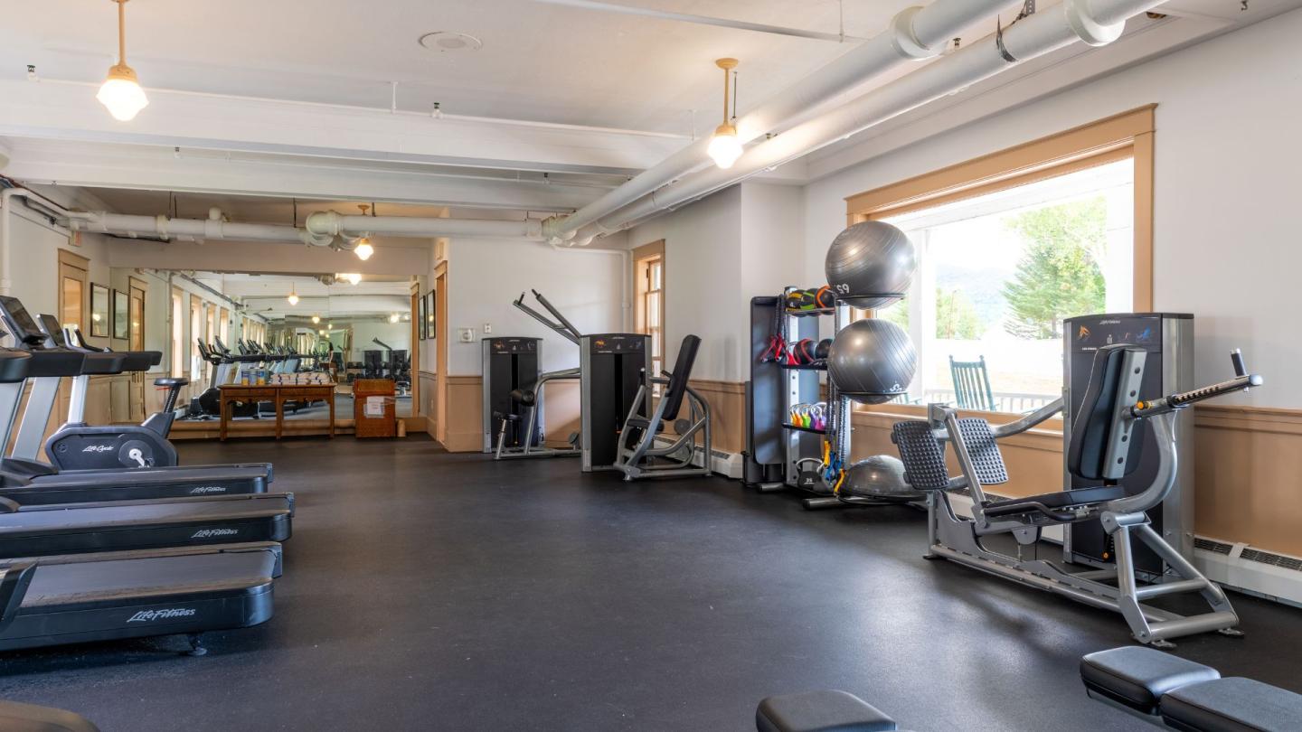Spacious gym with treadmills, exercise machines, and large windows.