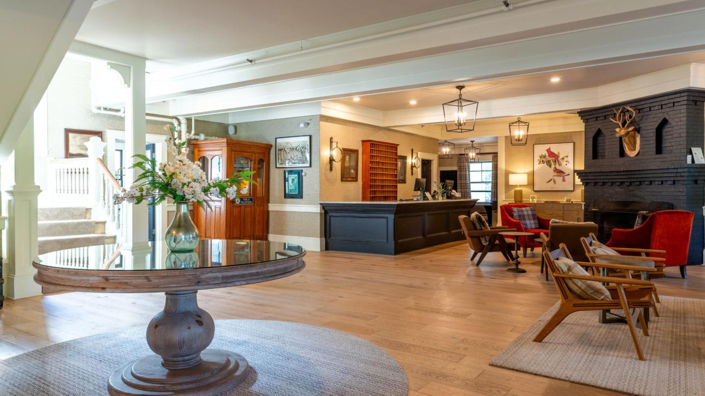 Spacious hotel lobby with seating area, flowers on table, and wooden decor.