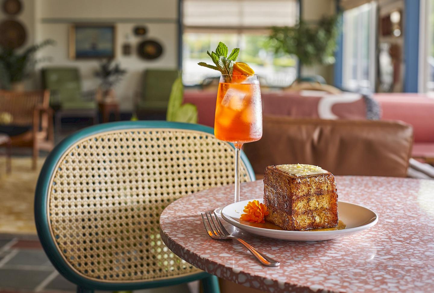 Toast and a cocktail on a terrazzo table in a cozy cafe setting.