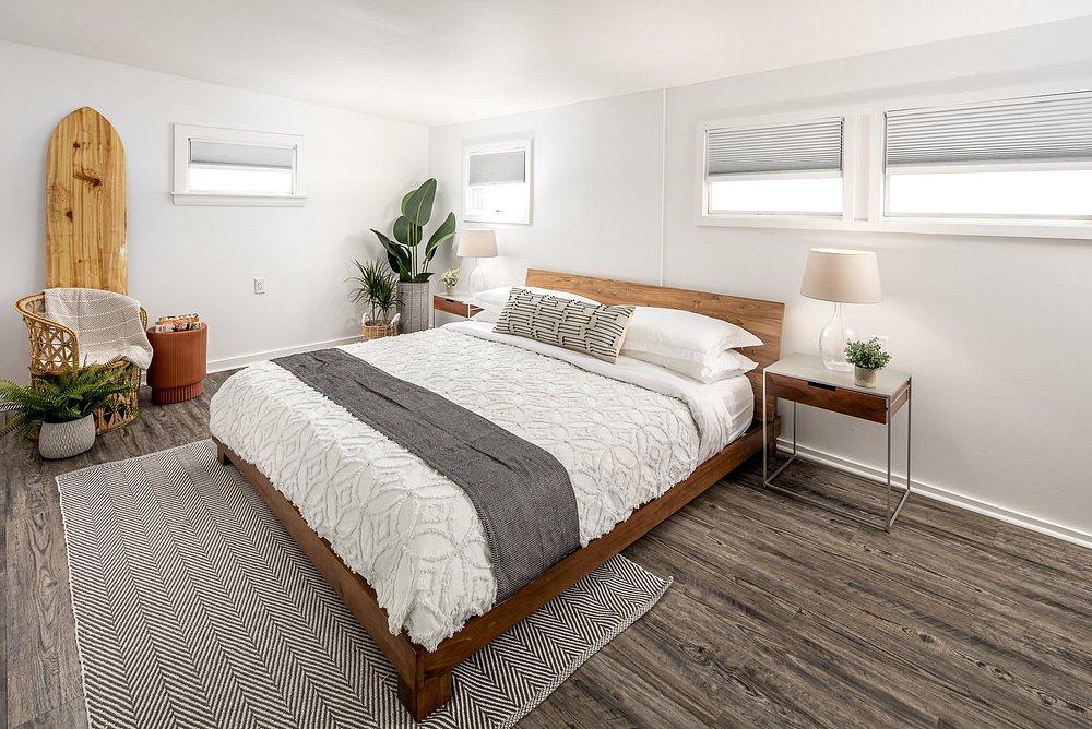 Cozy bedroom with a wooden bed, white linens, and indoor plants.