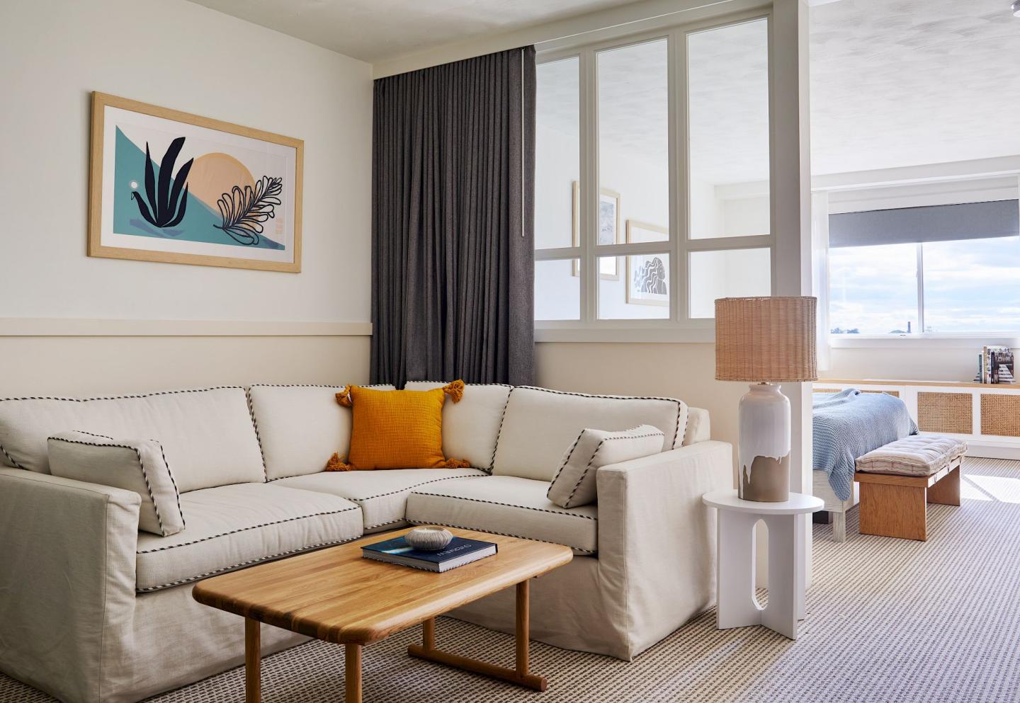 Cream-colored living room with a sofa, yellow pillow, art, and modern decor.