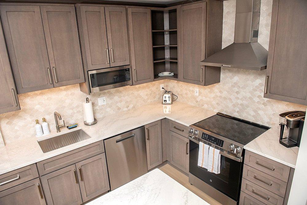 Stylish kitchen with wood cabinets, modern appliances, and marble countertops.