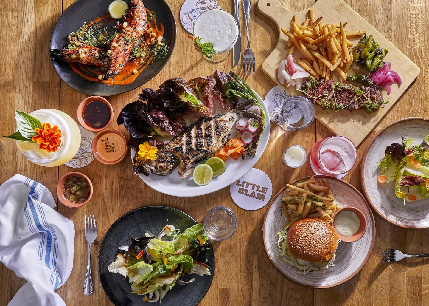 Assorted gourmet dishes with drinks on a wooden table.