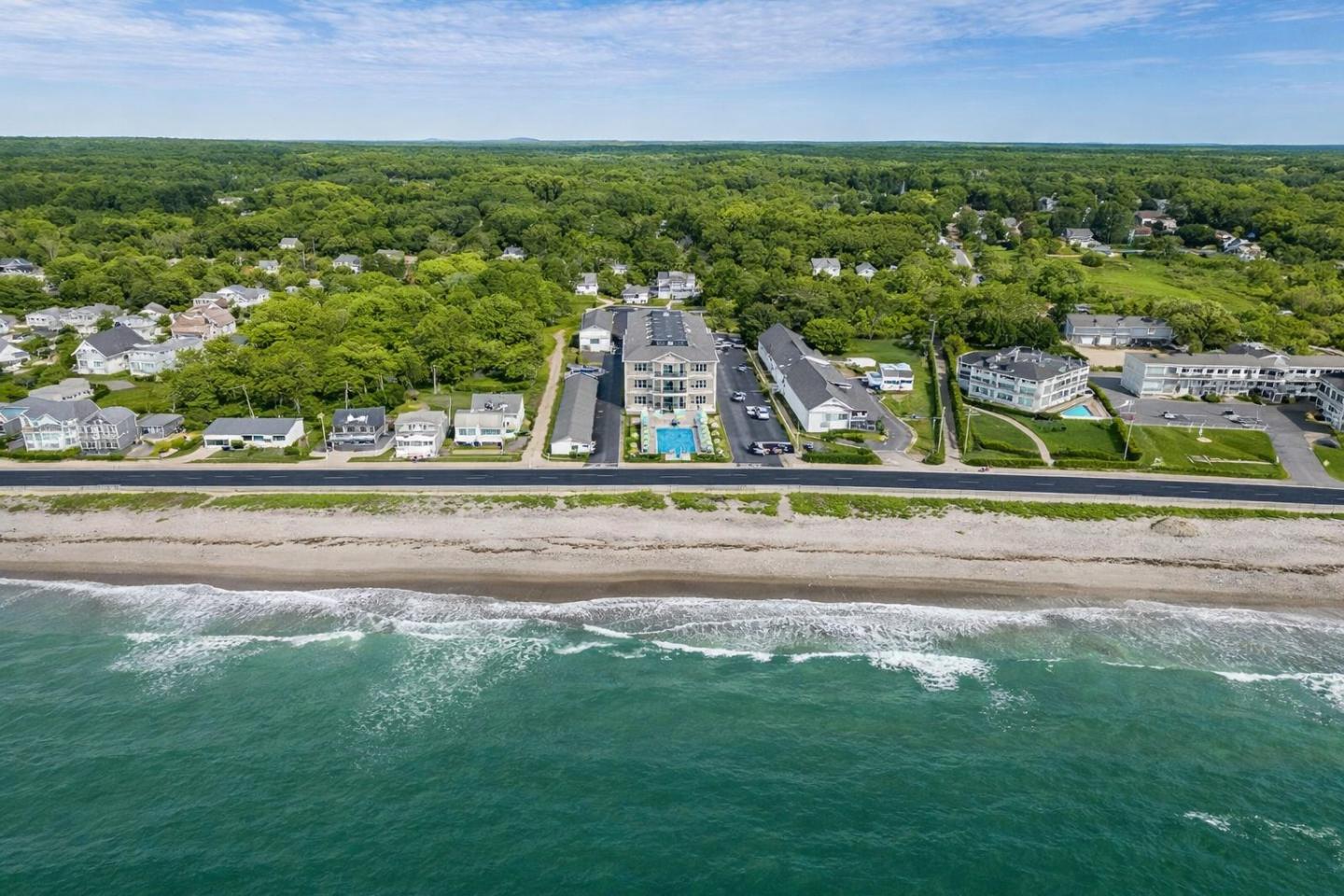 Coastal town with beachfront and green forest in the background.