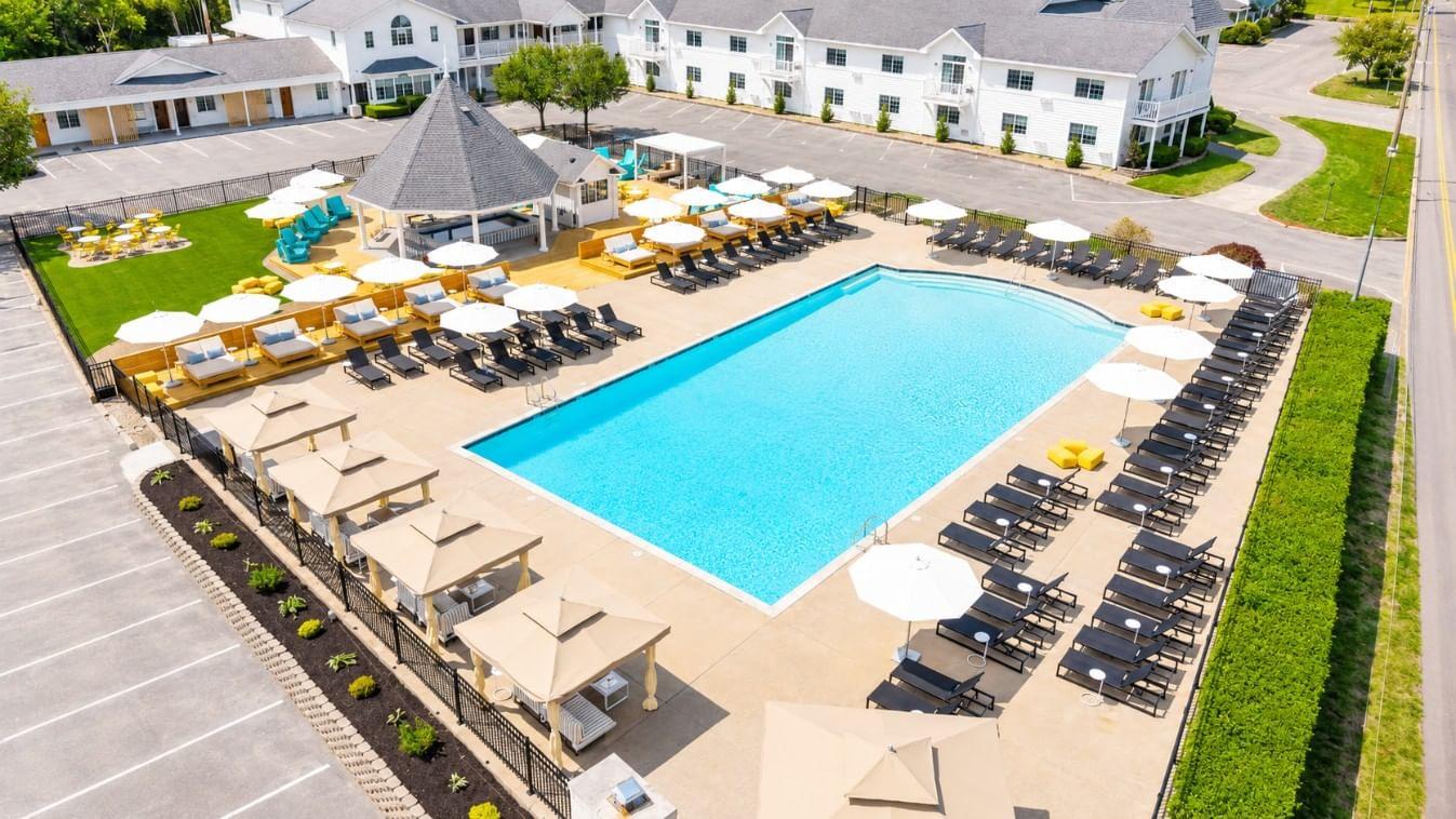 Outdoor pool with deck chairs, umbrellas, and a gazebo in a landscaped setting.