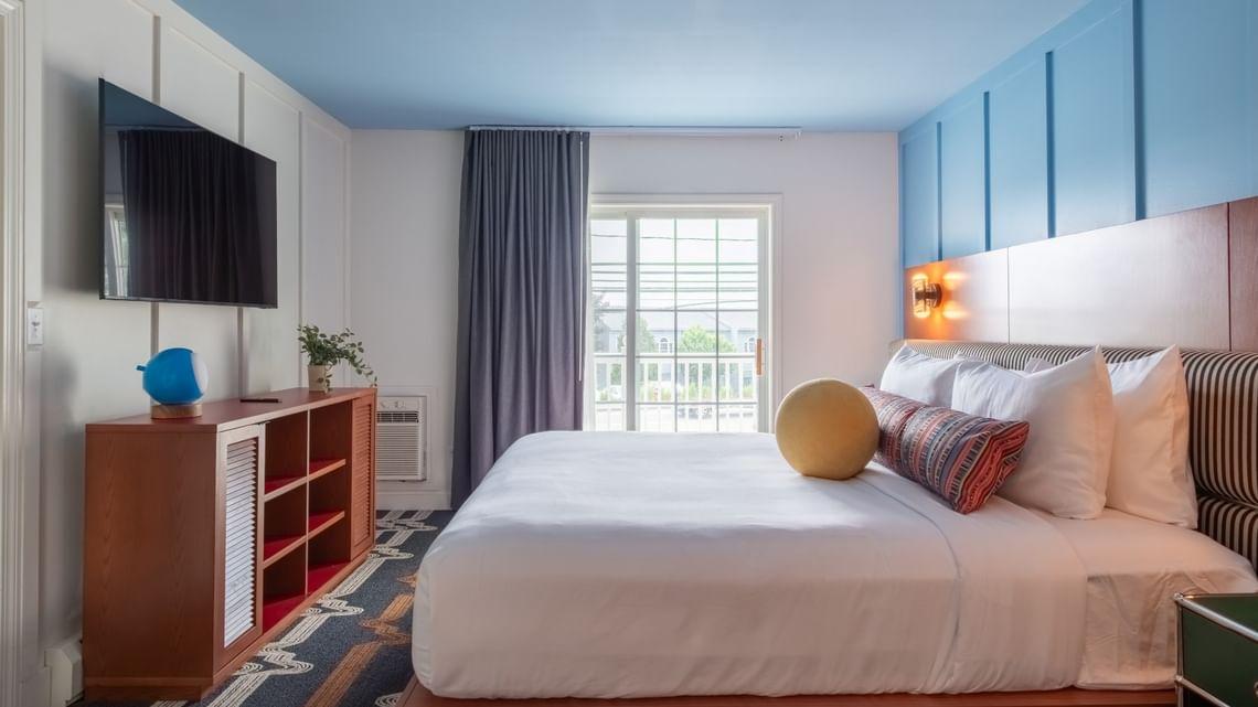 Cozy hotel room with blue accents, large bed, and natural light from a window.