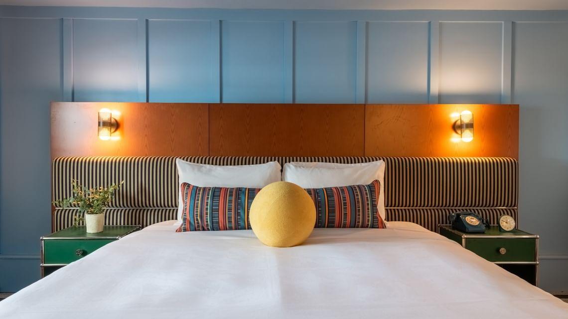 Stylish bedroom with blue walls and a cozy bed, accent pillows, and modern lighting.