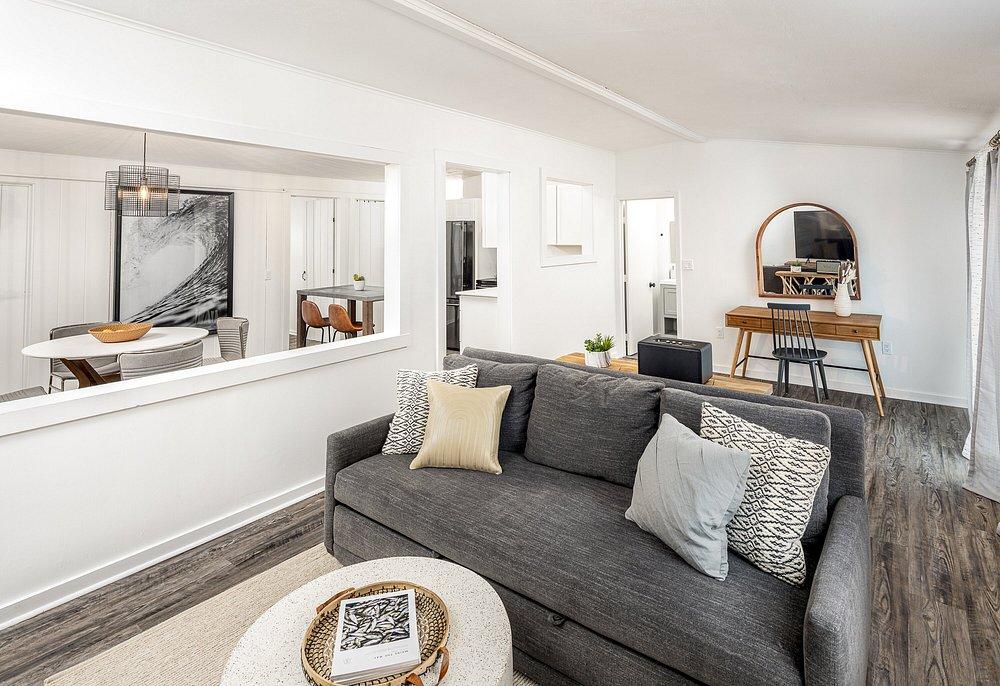 Modern living room with a gray sofa, cushions, and a round mirror on a wooden desk.