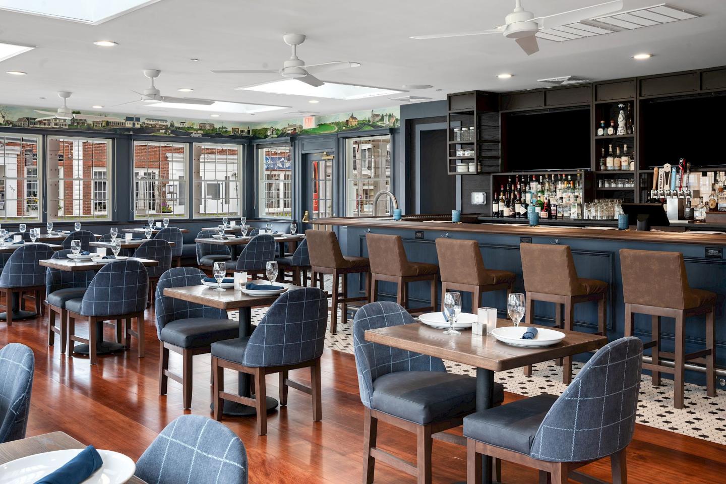 Upscale restaurant interior with blue chairs, wooden floors, and a stocked bar.