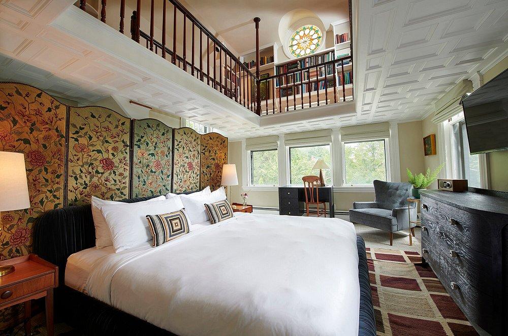 Spacious bedroom with a loft, large bed, patterned divider, and cozy seating area.
