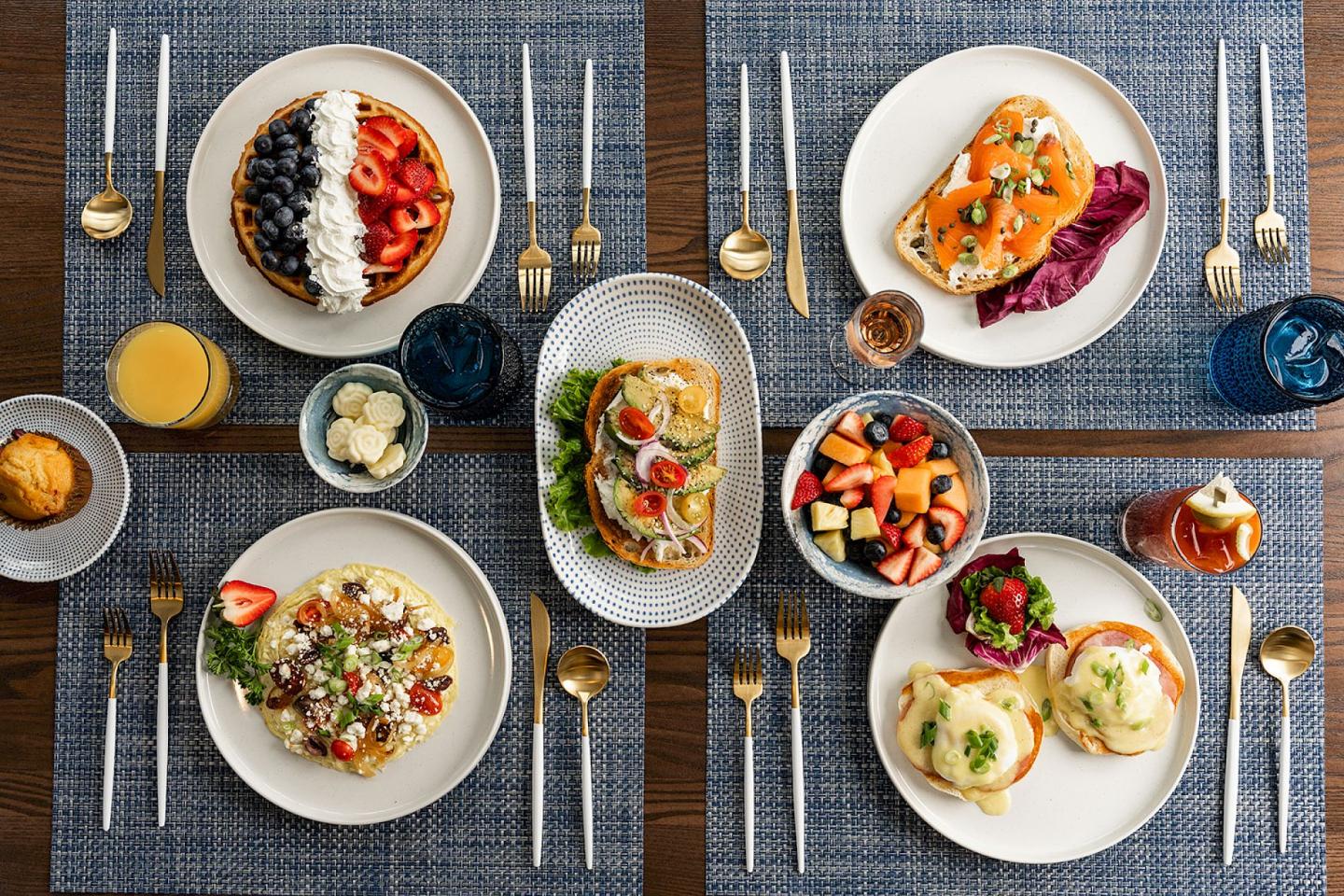 Assorted brunch dishes on a table, including waffles, toast, and fruit.